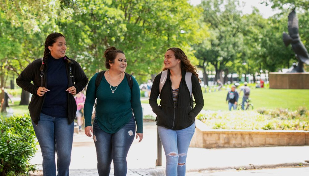 Three female students walking across campus. 